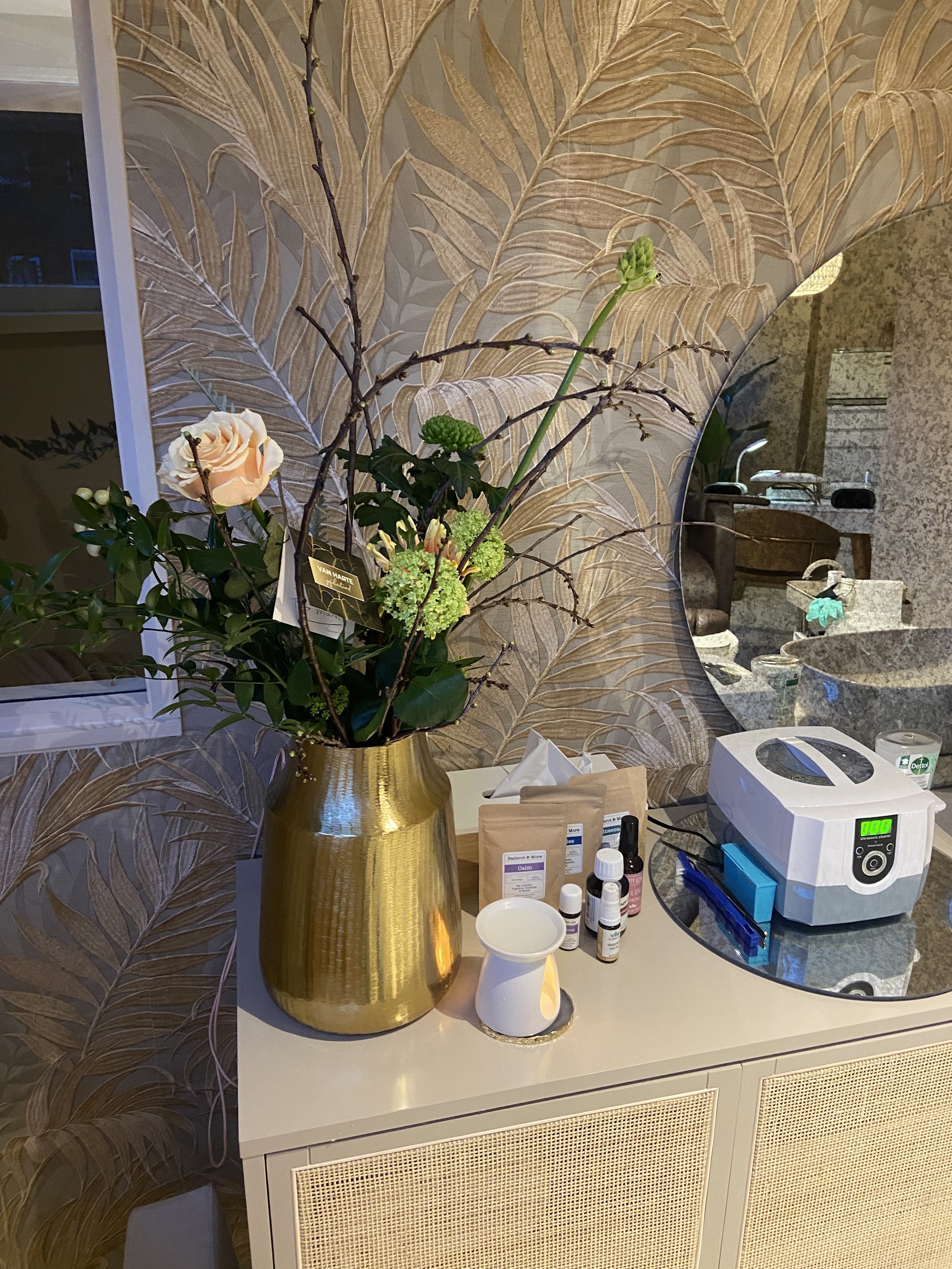 Bloemen in een gouden vaas, de ultrasoon sterilisator en producten in de salon